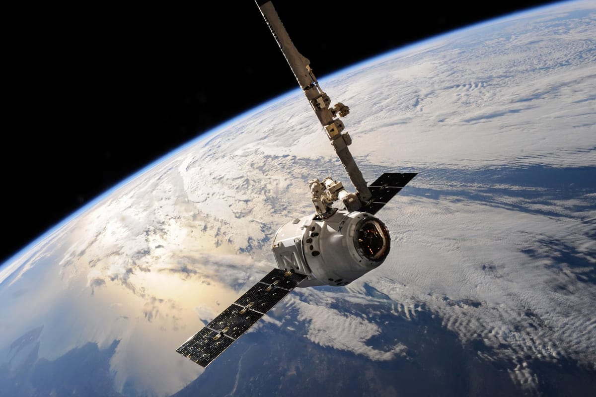 Satellit mit ausgeklappten Solarpaneelen über der von Wolken bedeckten Erde