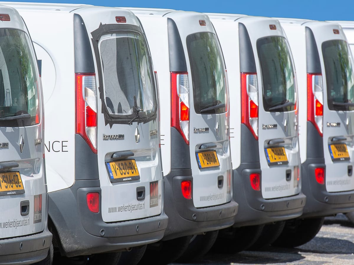 Reihe weißer Transporter, dicht hintereinander auf einem Betriebshof geparkt